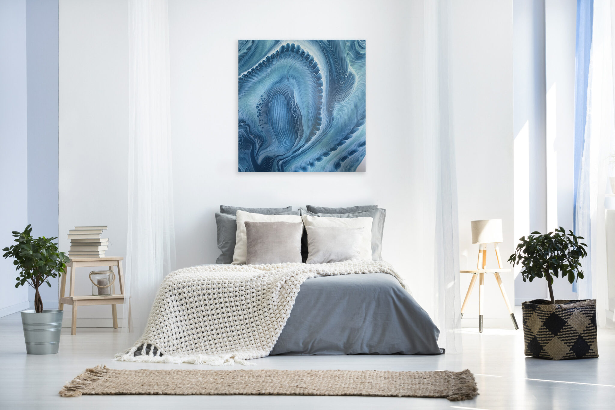 Beige blanket on king-size bed against wall with simple painting in bright bedroom interior with plants